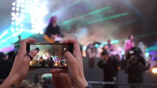 Midsection of woman using smart phone at music concert