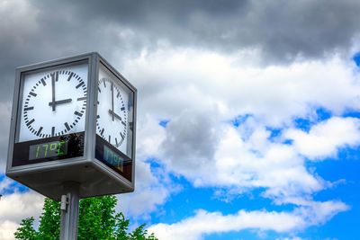 Low angle view of clock against sky