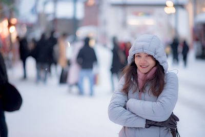 Portrait of woman standing on snow in city