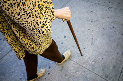 Single person walking across the street while holding a cane walking stick in new york city