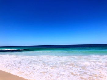 Scenic view of beach against clear blue sky