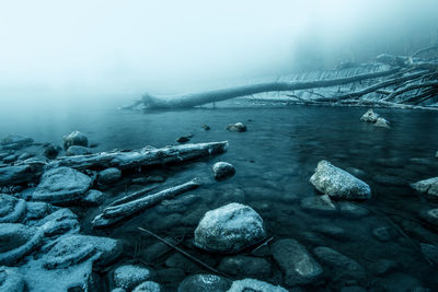 Scenic view of lake against sky during foggy weather