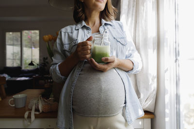 Pregnant woman standing by window at home