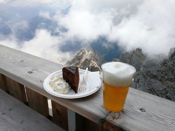 Cake and beer on table against mountains