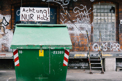 Garbage bin against graffiti on old building