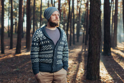 Thoughtful young man standing in forest