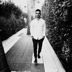 Portrait of young man standing on footpath