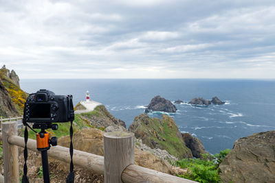 Digital camera by railing against sea