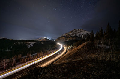 Light trails on road against sky at night