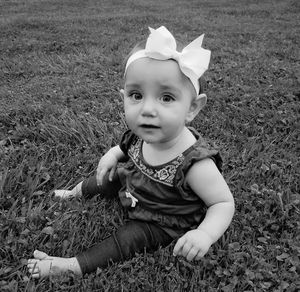 High angle portrait of baby girl sitting on grass at yard
