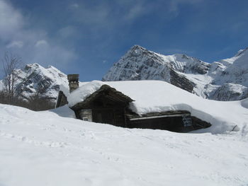 Built structure on snowcapped mountain against sky