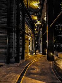 Illuminated footpath by building at night in city