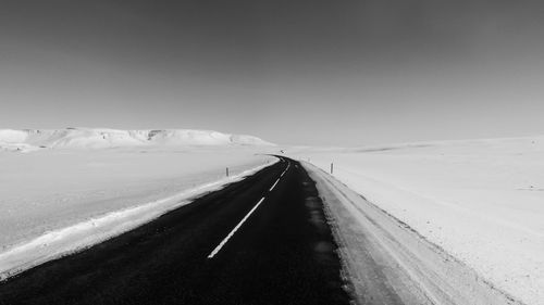 Road leading towards snowcapped mountain against sky