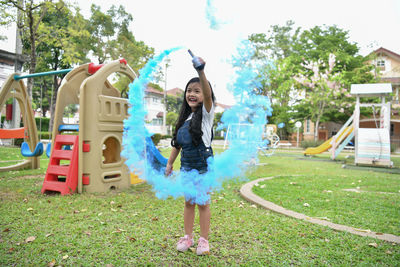 Full length of cheerful girl playing with distress flare at playground