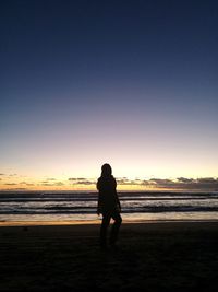 Silhouette man standing on beach against sky during sunset