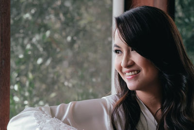 Close-up of happy woman looking through window