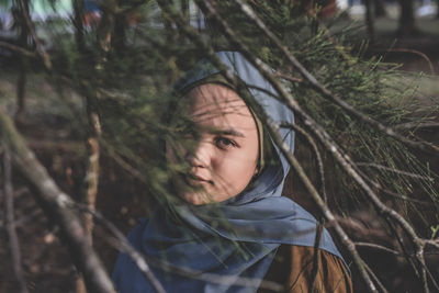 Portrait of young woman seen through branches in forest