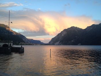 River water with rocky mountains against cloudy sky at dusk