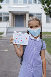 Portrait of girl standing against wall