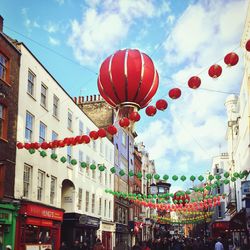 Lanterns hanging across city buildings against sky