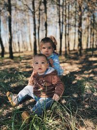 Portrait of siblings on field in forest