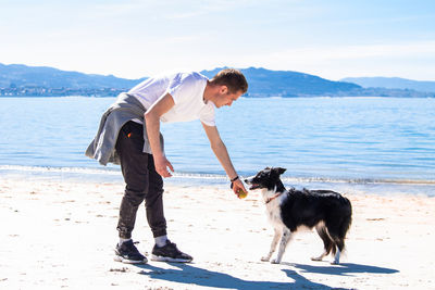 Young man playing with his dog on the beach