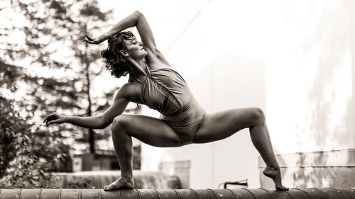 Full length of young woman exercising on field