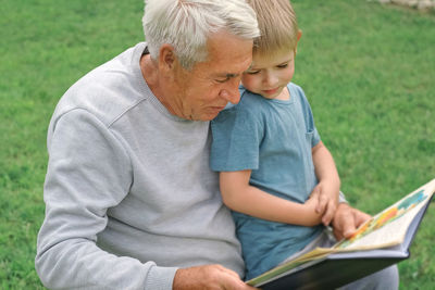 Young man using laptop while sitting on field