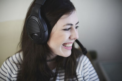 Close-up of smiling young woman wearing headphones at home