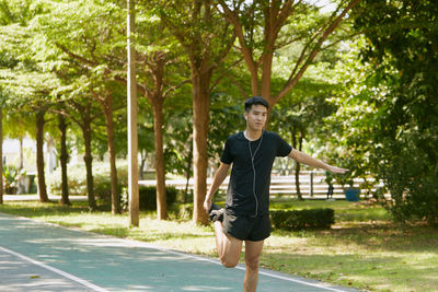 Young man stretching on road