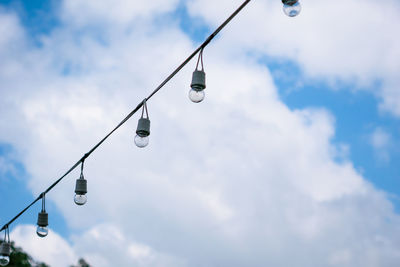 Low angle view of light bulbs hanging against sky