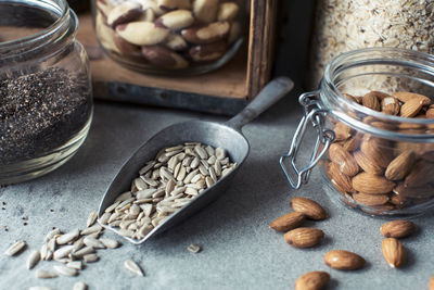 Close-up of seeds in serving scoop with almonds in jar on kitchen counter