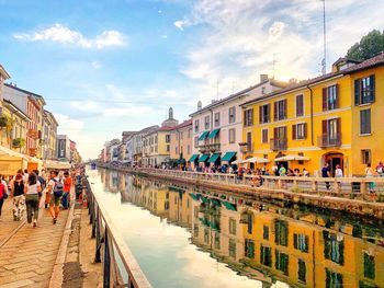 Group of people on navigli canal by buildings in milan, italy