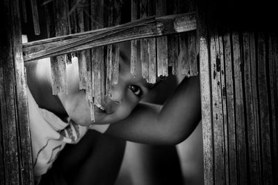 Portrait of boy peeking through wooden fence