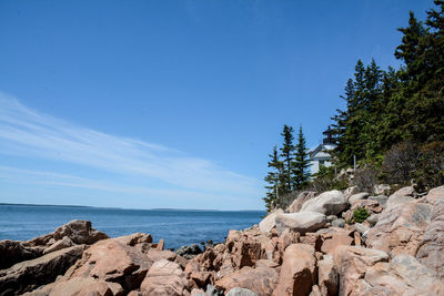 Rocks by sea against blue sky