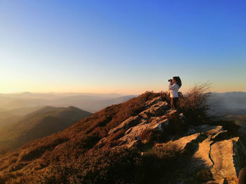 Rear view of man standing on mountain against clear sky