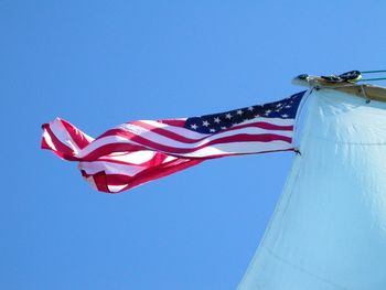 Low angle view of american flag against clear blue sky