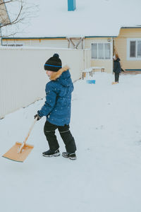 Boy cleans snow with a shovel on the street. a boy clears the road from snow in winter.