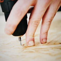 Close-up of hand using drill on wood