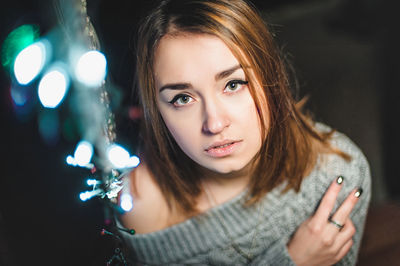 Portrait of beautiful woman standing by illuminated netting