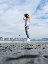 Full length of woman standing at beach against sky