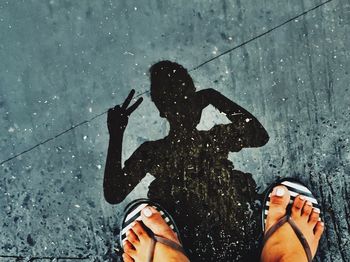 Low section of woman wearing flip flop while standing on road during rainy season