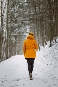 Rear view of woman walking on snow covered land