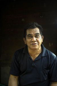 Portrait of man sitting against wood