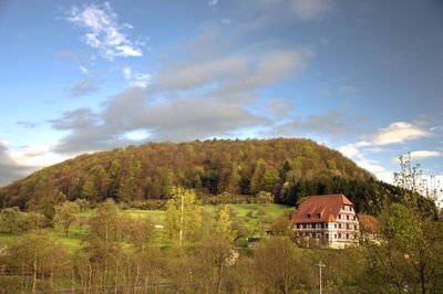 House amidst trees and buildings against sky