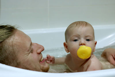 Cheerful father and son taking bath at bathroom