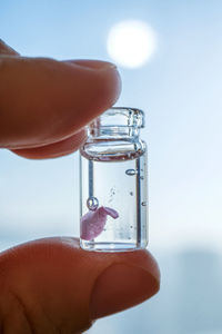 Close-up of hand holding bottle against blue background