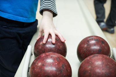 Midsection of boy holding bowling balls