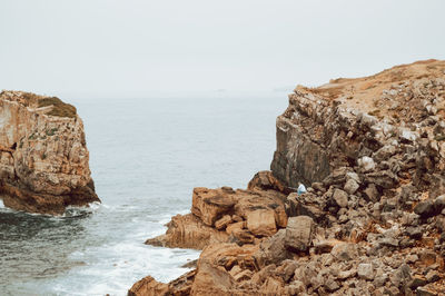 Rock formations by sea against clear sky