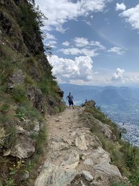 People on rock by mountain against sky